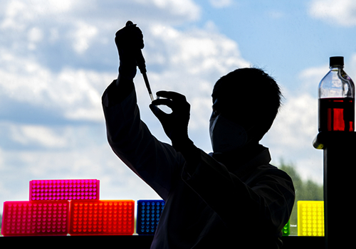 Silhouette of person working with pipette.